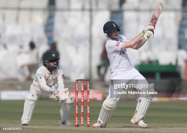 Harry Brook of England hits the ball towards the boundary, as Mohammad Rizwan of Pakistan watches on during Day Two of the Third Test between...