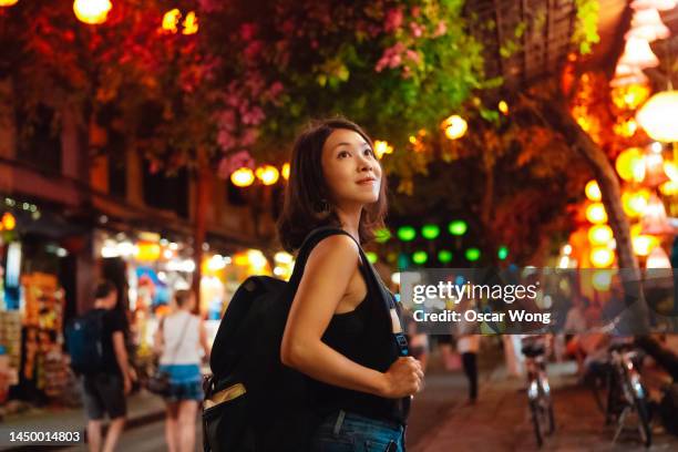 young asian woman with backpack walking at night market during chinese new year - chinese culture stock-fotos und bilder