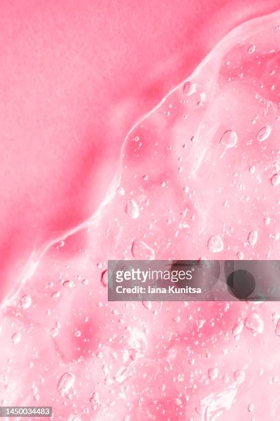 transparent pink moisture serum for face smudged. hydrating hyaluronic acid. antibacterial gel with bubbles. cosmetic products for makeup and skin care. cosmetology. vertical. - glossy lips stock pictures, royalty-free photos & images