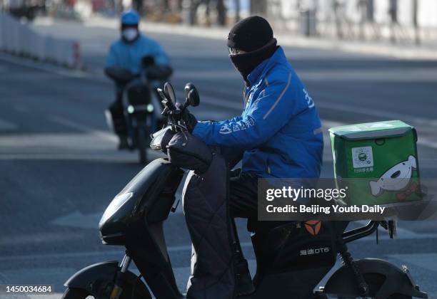 Courier rides an electric bicycle with packages along a street on December 17, 2022 in Beijing, China. Couriers from other regions of China have been...