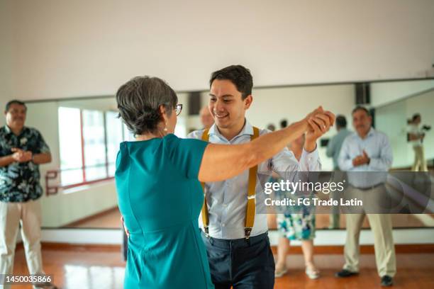 femme senior dansant avec un professeur de danse dans un studio de danse - danse de salon photos et images de collection