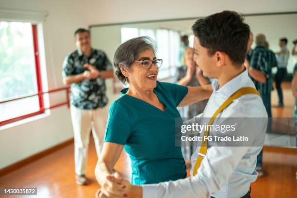 donna senior che balla con l'istruttore di danza in uno studio di danza - dance teacher foto e immagini stock