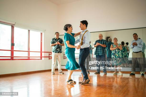 femme senior dansant avec un professeur de danse dans un studio de danse - danse de salon photos et images de collection