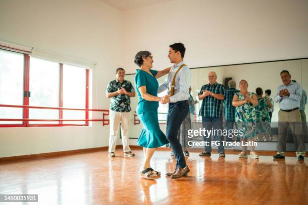 senior woman dancing with dancing instructor at a dance studio - ballroom stockfoto's en -beelden