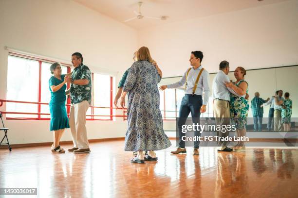un jeune professeur de danse aide des élèves plus âgés dans un studio de danse - danse de salon photos et images de collection
