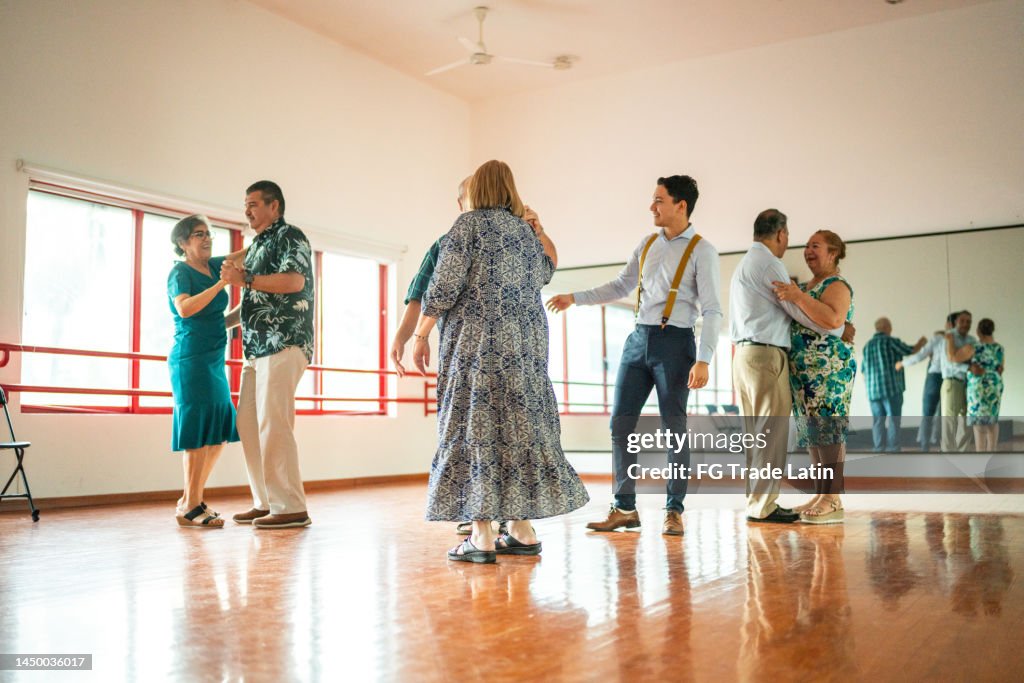 Young dance instructor helping senior students at a dance studio