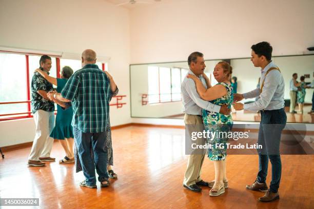 young dance instructor helping senior students at a dance studio - latin dance class stock pictures, royalty-free photos & images