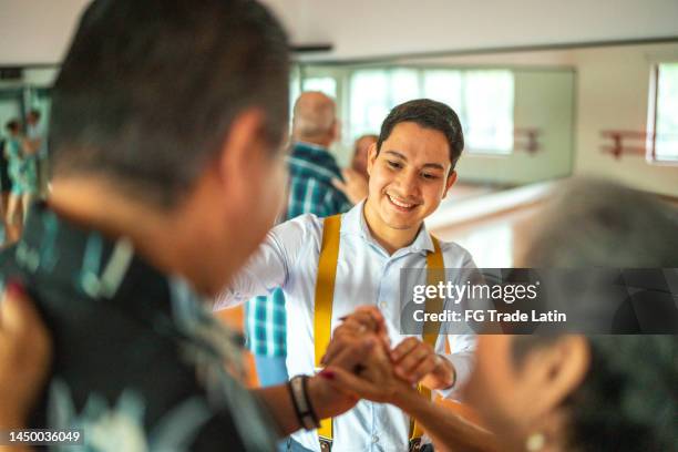 young dance instructor helping senior couple student at a dance studio - swing dance stock pictures, royalty-free photos & images