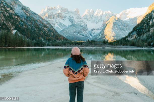 woman standing near  lago di braies in winter - standing water stockfoto's en -beelden