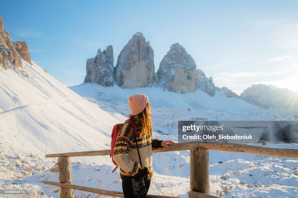 Frau, die im Winter auf dem Hintergrund der Drei Zinnen wandert