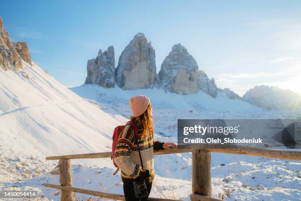 frau, die im winter auf dem hintergrund der drei zinnen wandert - cortina stock-fotos und bilder