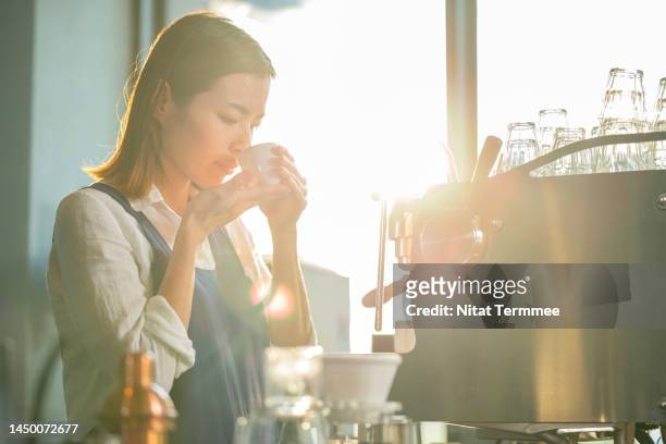 maintain a strong customer base with the taste and quality of coffee. a female japanese coffee shop owner holding a cup while smelling freshly roasted coffee to control the quality of coffee in every cup. - taste test stock pictures, royalty-free photos & images