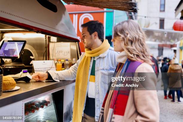 young couple buying street food - food truck payments stock pictures, royalty-free photos & images