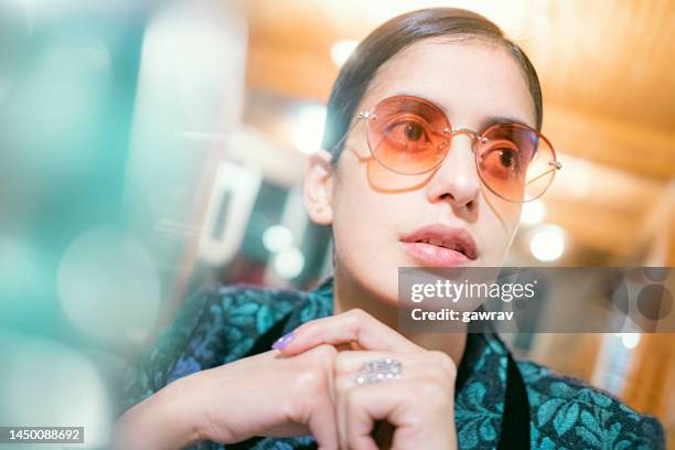 bachelorette young woman takes a break in a cafe. - gekleurde-zonnebril stockfoto's en -beelden