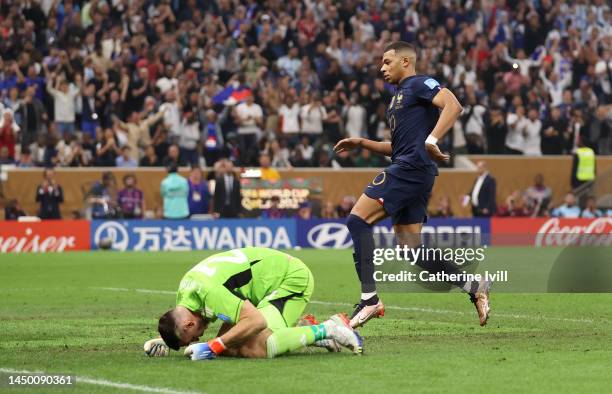 Kylian Mbappe of France runs to pick up the ball after the team's first goal while Emiliano Martinez of Argentina shows dejection during the FIFA...