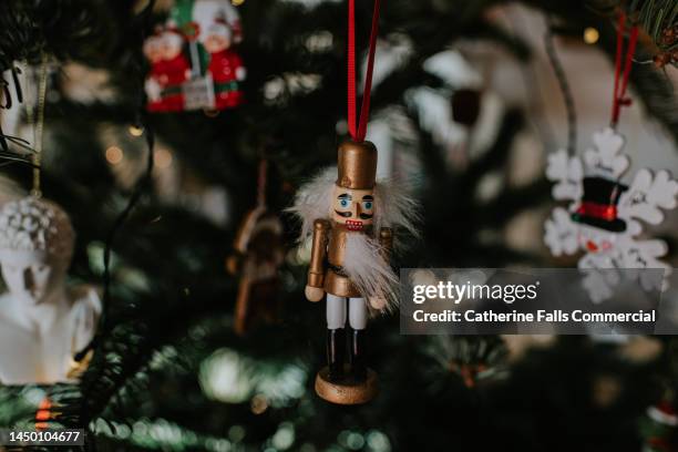 a traditional, wooden nutcracker decoration hangs from a christmas tree - vestido decorado fotografías e imágenes de stock