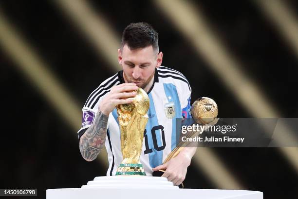 Lionel Messi of Argentina kisses the FIFA World Cup Qatar 2022 Winner's Trophy while holding the adidas Golden Boot award after the FIFA World Cup...