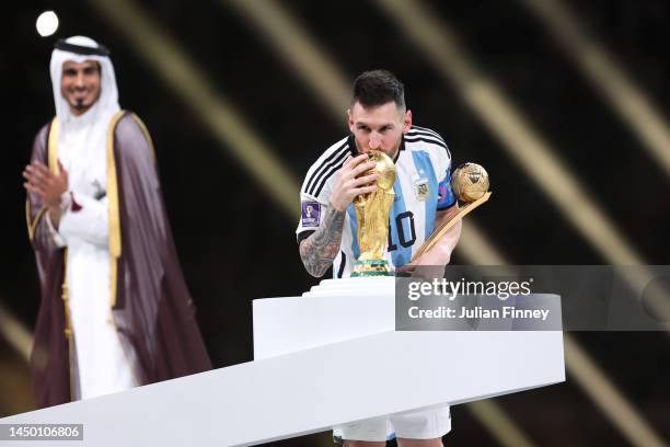 Lionel Messi of Argentina kisses the FIFA World Cup Qatar 2022 Winner's Trophy while holding the adidas Golden Boot award after the FIFA World Cup...