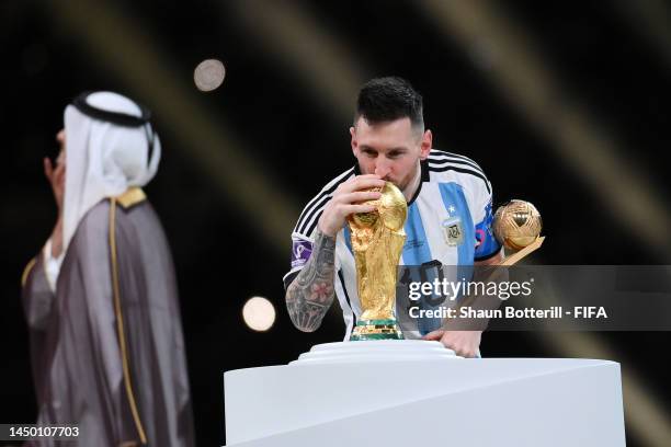 Lionel Messi of Argentina kisses the FIFA World Cup Qatar 2022 Winner's Trophy while holding the adidas Golden Boot award after the FIFA World Cup...