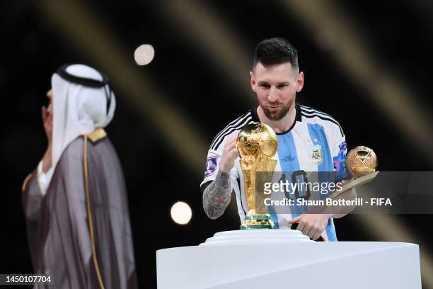Lionel Messi of Argentina kisses the FIFA World Cup Qatar 2022 Winner's Trophy while holding the adidas Golden Boot award after the FIFA World Cup...