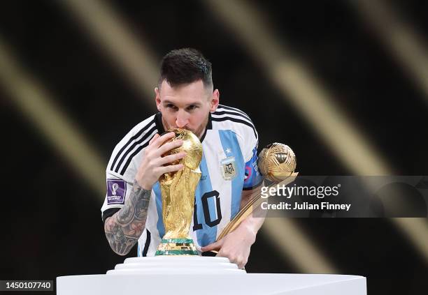 Lionel Messi of Argentina kisses the FIFA World Cup Qatar 2022 Winner's Trophy while holding the adidas Golden Boot award after the FIFA World Cup...