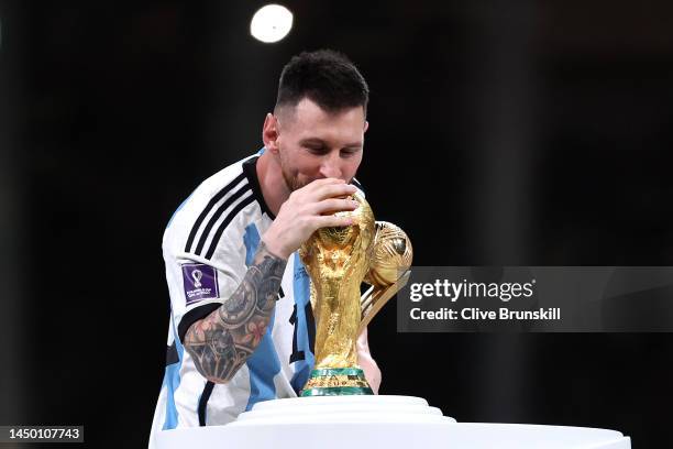 Lionel Messi of Argentina kisses the FIFA World Cup Qatar 2022 Winner's Trophy while holding the adidas Golden Boot award after the FIFA World Cup...