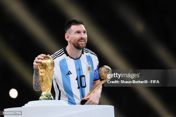 Lionel Messi of Argentina touches the FIFA World Cup Qatar 2022 Winner's Trophy while holding the adidas Golden Boot award after the FIFA World Cup...