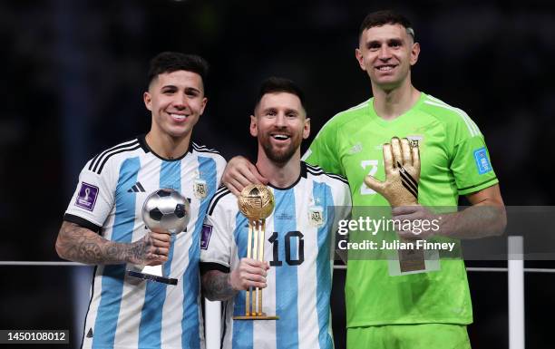 Enzo Fernandez, Lionel Messi and Emiliano Martinez of Argentina pose for a photo with the FIFA Young Player award, the adidas Golden Ball and the...