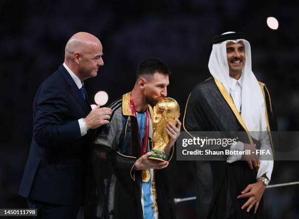 Lionel Messi of Argentina kisses the FIFA World Cup Qatar 2022 Winner's Trophy as he interacts with Gianni Infantino, President of FIFA, and Sheikh...