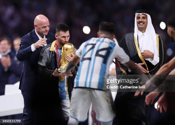 Lionel Messi of Argentina kisses the FIFA World Cup Qatar 2022 Winner's Trophy as he interacts with Gianni Infantino, President of FIFA, and Sheikh...