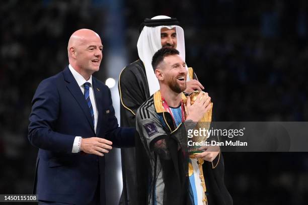 Lionel Messi of Argentina holds the FIFA World Cup Qatar 2022 Winner's Trophy as he interacts with Gianni Infantino, President of FIFA, and Sheikh...