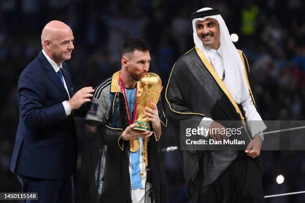 Lionel Messi of Argentina kisses the FIFA World Cup Qatar 2022 Winner's Trophy as Gianni Infantino, President of FIFA, and Sheikh Tamim bin Hamad Al...