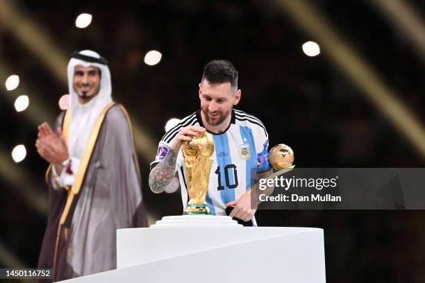 Lionel Messi of Argentina kisses the FIFA World Cup Qatar 2022 Winners' Trophy while holding the adidas Golden Boot award after the FIFA World Cup...