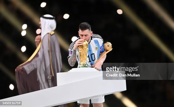 Lionel Messi of Argentina kisses the FIFA World Cup Qatar 2022 Winners' Trophy while holding the adidas Golden Boot award after the FIFA World Cup...