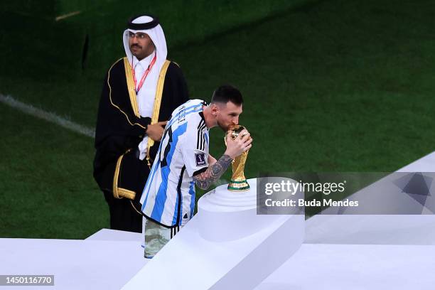 Lionel Messi of Argentina kisses the FIFA World Cup Qatar 2022 Winners' Trophy while holding the adidas Golden Boot award after the FIFA World Cup...