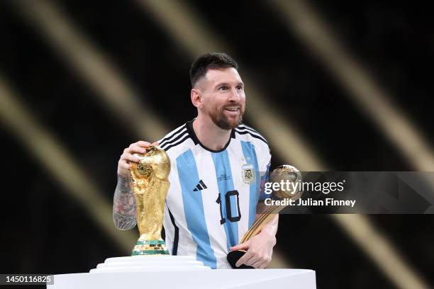 Lionel Messi of Argentina kisses the FIFA World Cup Qatar 2022 Winners' Trophy while holding the adidas Golden Boot award after the FIFA World Cup...