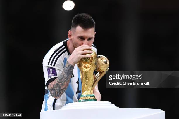 Lionel Messi of Argentina kisses the FIFA World Cup Qatar 2022 Winners' Trophy while holding the adidas Golden Boot award after the FIFA World Cup...