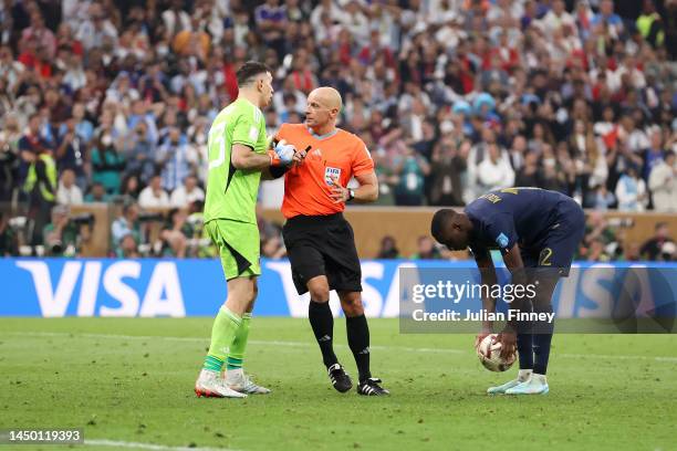 Emiliano Martinez of Argentina is prevented by referee Szymon Marciniak from speaking to Randal Kolo Muani of France in the penalty shootout during...