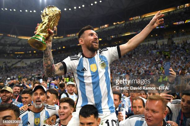 Lionel Messi of Argentina celebrates with the FIFA World Cup Qatar 2022 Winner's Trophy on the shoulders of former teammate Sergio Aguero after the...