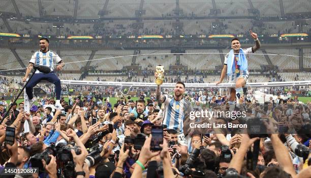 Lionel Messi of Argentina celebrates with the FIFA World Cup Qatar 2022 Winner's Trophy on the shoulders of former teammate Sergio Aguero after the...