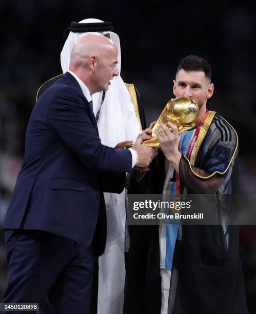 Lionel Messi of Argentina kisses the FIFA World Cup Qatar 2022 Winner's Trophy as Gianni Infantino, President of FIFA, and Sheikh Tamim bin Hamad Al...