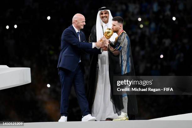 Lionel Messi of Argentina kisses the FIFA World Cup Qatar 2022 Winner's Trophy as Gianni Infantino, President of FIFA, and Sheikh Tamim bin Hamad Al...