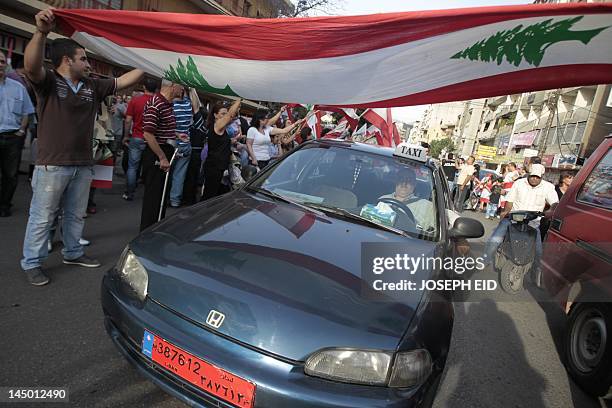 Lebanese taxi driver maneuvers his vehicle under a large national flag during a rally in support of the army in the Beirut northern suburb of Dora on...