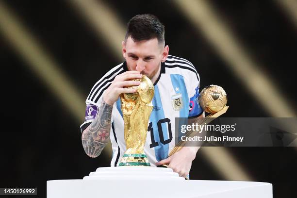 Lionel Messi of Argentina kisses the FIFA World Cup Qatar 2022 Winners' Trophy while holding the adidas Golden Boot award after the FIFA World Cup...