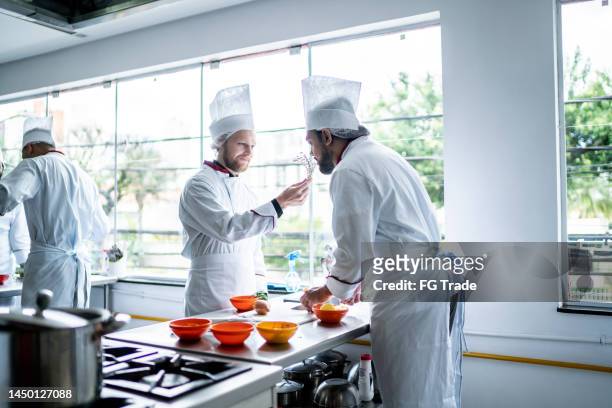coworkers cooking together in a commercial kitchen - chef smelling food stockfoto's en -beelden