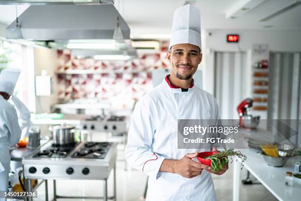 portrait of a chef holding some herbs at the kitchen - person of color stock pictures, royalty-free photos & images