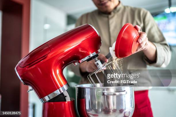 chef pouring ingredients into a mixing bowl - electric mixer stock pictures, royalty-free photos & images