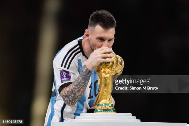 Lionel Messi of Argentina kisses the FIFA World Cup trophy as he collects the Golden Ball award following the FIFA World Cup Qatar 2022 Final match...