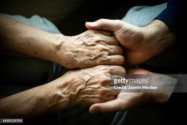 close up of son holding his mothers hands - frau hände pflege stock-fotos und bilder