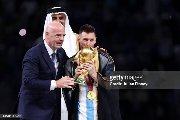 Lionel Messi of Argentina kisses the FIFA World Cup Qatar 2022 Winner's Trophy as Gianni Infantino, President of FIFA, and Sheikh Tamim bin Hamad Al...